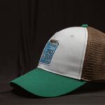 A stylish vintage baseball cap with green peak and mesh detailing, featuring a Space Tour patch.
