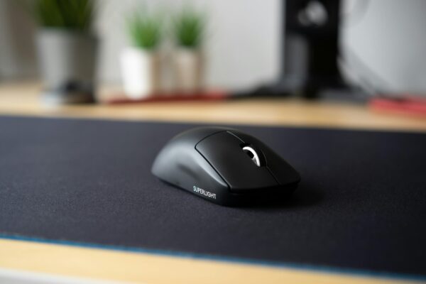 Sleek black wireless mouse on a modern desk with a blurred background, emphasizing minimalism.